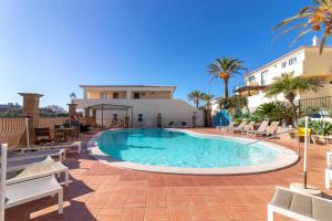 einen Pool in einem Resort mit Stühlen und Palmen in der Unterkunft Townhouse nº30 with fantastic sea views in Ferragudo