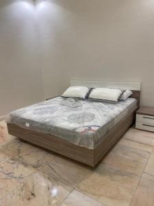 Bett in einem Zimmer mit einer weißen Wand in der Unterkunft شاليه ألو in Al Bukayriyah