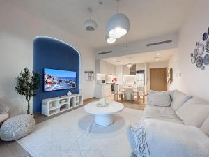 een woonkamer met een witte bank en een blauwe muur bij Trophy - Mykonos-Inspired La Mer Suite in Dubai