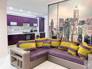 a living room with a purple couch with yellow pillows at RentHouse Apartments Deep Purple in Chişinău