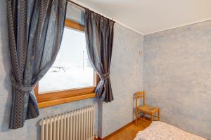 una piccola camera da letto con finestra e sedia di Appartamento Piz Filone a Livigno