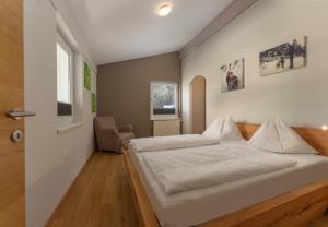 sypialnia z dużym białym łóżkiem i krzesłem w obiekcie Appartement Schneider by Schladming-Appartements w Schladming