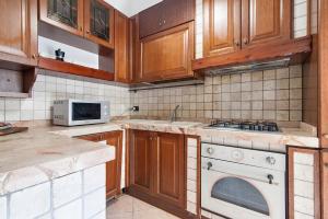 cocina con armarios de madera y horno de fogón blanco en Le 2 Palme Family House - Lecce Selection, en Lecce
