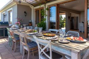 une grande table en bois avec des assiettes de nourriture sur une terrasse dans l'établissement Quinta dos Caneiros Luxury villa Ocean views walk to beach, à Ferragudo