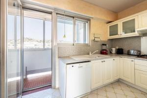 une cuisine avec des placards blancs et une grande fenêtre dans l'établissement Emilie - panoramic sea views beach facing paradise, à Vallauris