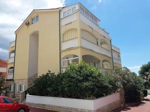 a tall yellow building with a car parked in front of it at Apartment Oasis - Novalja in Novalja