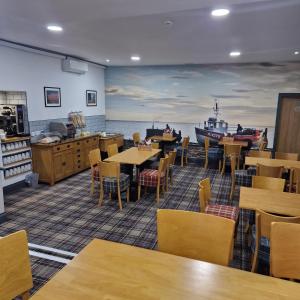a restaurant with tables and chairs and a painting of a boat at Claxton Hotel in Redcar