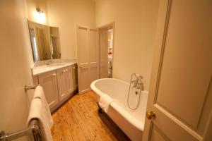 a white bathroom with a tub and a sink at Old Coastguards - Stunning Historic Cottage in Totland +34 photos