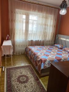 a bedroom with a bed and a window with a rug at 2 комнатная уютная квартира в 18 мкрн in Shymkent