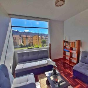 uma sala de estar com um sofá e uma grande janela em Delgado's home em Cusco
