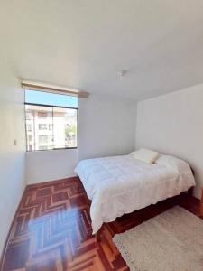 um quarto branco com uma cama e uma janela em Delgado's home em Cusco