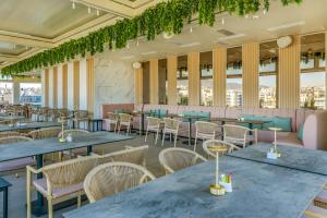 a restaurant with blue tables and chairs and windows at LUX&EASY Signature Syggrou 234 in Athens