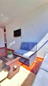 uma sala de estar com um sofá azul e uma televisão em Delgado's home em Cusco