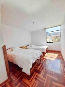 um quarto com quatro camas e uma janela em Delgado's home em Cusco