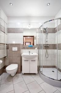 La salle de bains est pourvue de toilettes, d'un lavabo et d'une douche. dans l'établissement Osiedle Zwycięstwa Standard Apartment, à Poznań