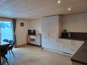 eine Küche mit weißen Schränken, einem Tisch und einer Mikrowelle in der Unterkunft Alpenbauernhaus Konzett in Schruns-Tschagguns