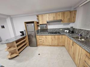 uma cozinha com armários de madeira e um frigorífico de aço inoxidável em New Dawn Rio em Riobamba