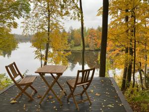 two chairs and a table on a dock near a lake at Divas Upes in Koknese