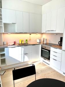 a white kitchen with white cabinets and a chair in it at Downtown Suite in Helsinki