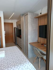 Dormitorio con cama, escritorio y TV en Barra Caravela Studio, en Salvador