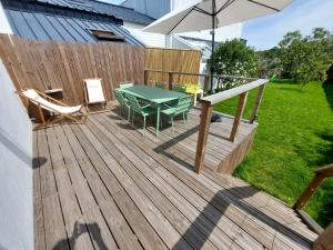 une terrasse en bois avec une table, des chaises et un parasol dans l'établissement Ker-Jeannette, familiale, chaleureuse, plages à 2 km, à Clohars-Carnoët