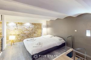 a bedroom with a bed and a stone wall at Loft Gambetta 33 Fshh in Nice