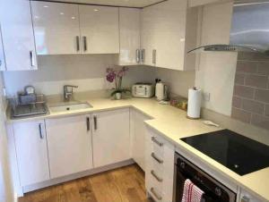 eine Küche mit weißen Schränken und einem Waschbecken in der Unterkunft Bramble cottage with free parking in Bridgnorth