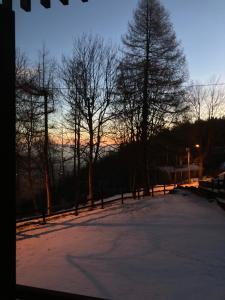 a snow covered field with trees and the sunset at All’angolo delle alpi in Montoso