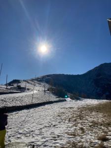 een persoon die bovenop een met sneeuw bedekte heuvel staat bij All’angolo delle alpi in Montoso