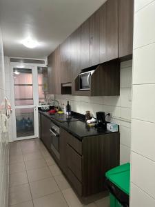 a kitchen with wooden cabinets and a black counter top at Departamento Playa Brava 3D 2B in Iquique