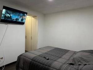 a bedroom with a bed with a flat screen tv on the wall at Departamento Playa Brava 3D 2B in Iquique