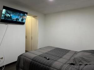een slaapkamer met een bed en een flatscreen-tv aan de muur bij Departamento Playa Brava 3D 2B in Iquique