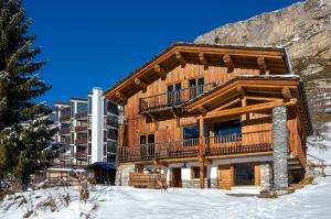 a log cabin in the snow in front of a building at Chalet Carte Blanche Thovex in Val-d'Isère
