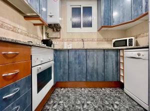 a small kitchen with white appliances and blue cabinets at Elegantniy Poble Sec in Barcelona