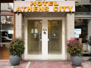 a hotel entrance with two potted plants in front of it at Athens City Hotel in Athens