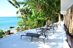 a row of black benches sitting on the beach at Pousada Ponta Das Pedras in Morro de São Paulo