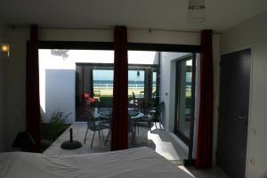 - une chambre avec un lit et un balcon avec une table et des chaises dans l'établissement Gites "Bord de Mer" PMR ou "Arromanches" 2 chambres en FRONT DE MER à Asnelles , 3km d'Arromanches, 10km de Bayeux, à Saint-Côme-de-Fresné
