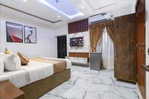 een slaapkamer met een kingsize bed en een televisie bij God's Touch Apartments Remi Fani Kayode GRA. Ikeja in Ikeja