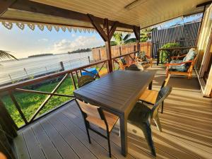 ウツロアにあるFARE Miti en bord de mer Fare Tepua Lodgeのテーブルと椅子が備わるデッキから水辺の景色を望めます。