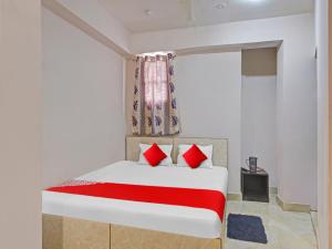Un dormitorio con una cama con almohadas rojas y una ventana en OYO Flagship Sona Residency en Ranchi