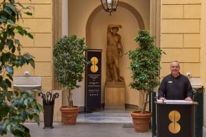 Un uomo in piedi su un podio di fronte a un edificio di Borghese Contemporary Hotel a Roma