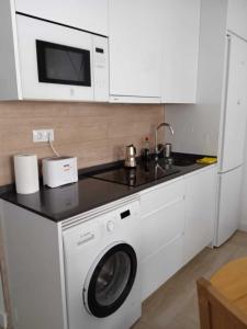 a kitchen with a washing machine and a microwave at Precioso apartamento recién reformado in Madrid