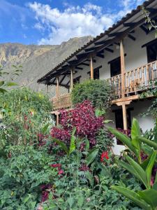 a house with a balcony and some flowers at El Albergue Ollantaytambo in Ollantaytambo