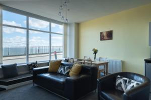 a living room with a table and chairs and a large window at Central Tenby North Beach Apartment with Parking in Pembrokeshire