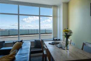 a living room with a table and a large window at Central Tenby North Beach Apartment with Parking in Pembrokeshire