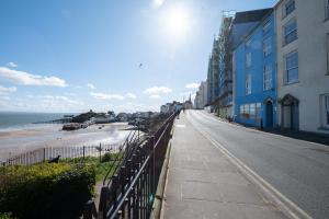 an empty street next to a beach with a blue building at Central Tenby North Beach Apartment with Parking in Pembrokeshire