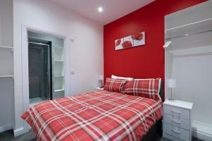 a red bedroom with a bed and a red wall at Central Tenby North Beach Apartment with Parking in Pembrokeshire