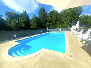 une grande piscine avec des chaises et un parasol dans l'établissement Camping Moulin du Pommier, à Saulgond