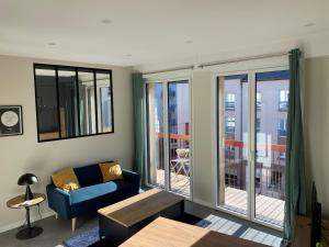 a living room with a couch and a table and windows at Le Faubourg in Rodez