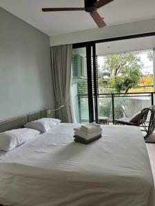 a bedroom with a white bed with a large window at Cassia Residences in Phuket
